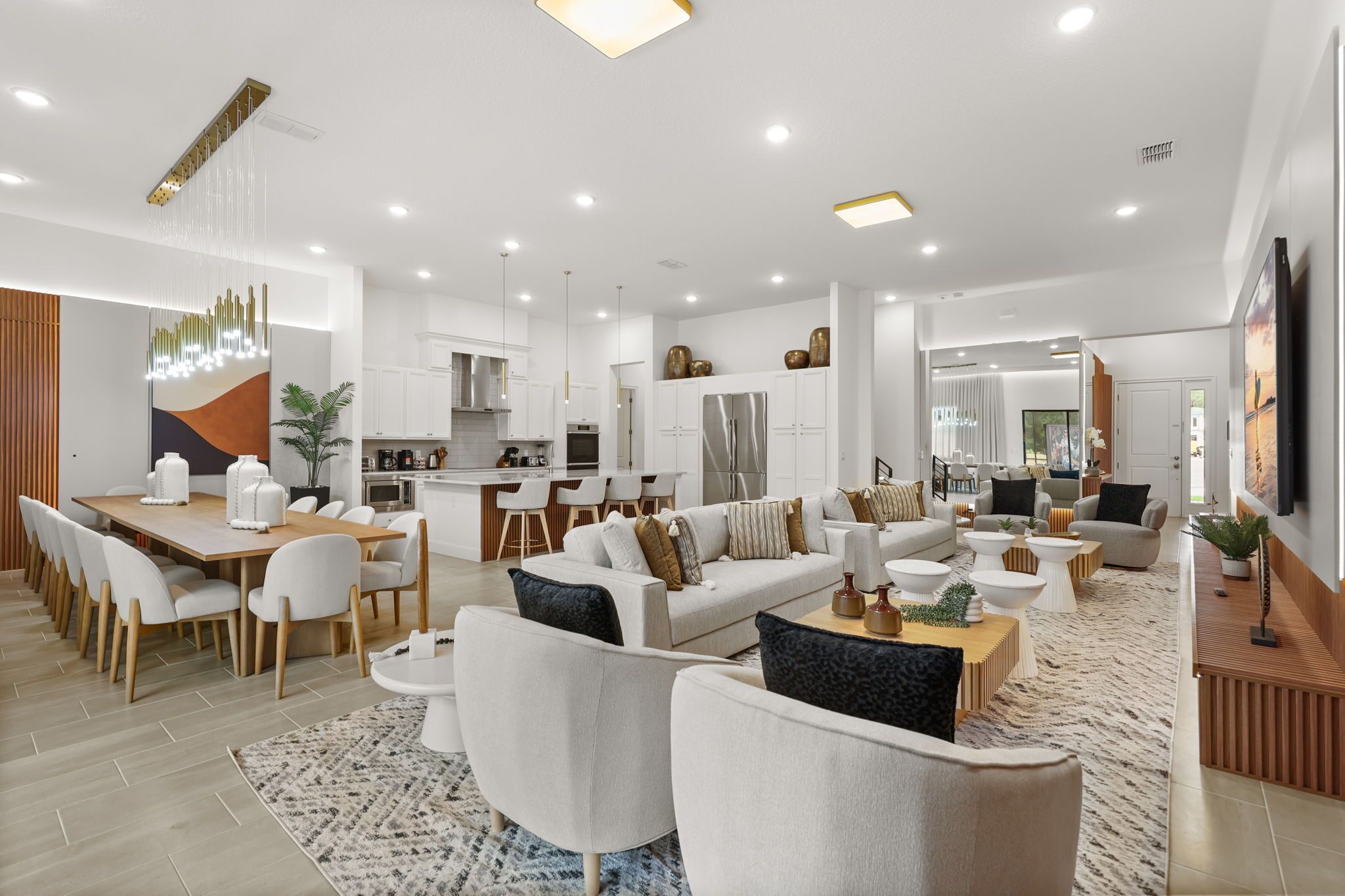 A modern living room with a dining area, kitchen, and a large window providing natural light.