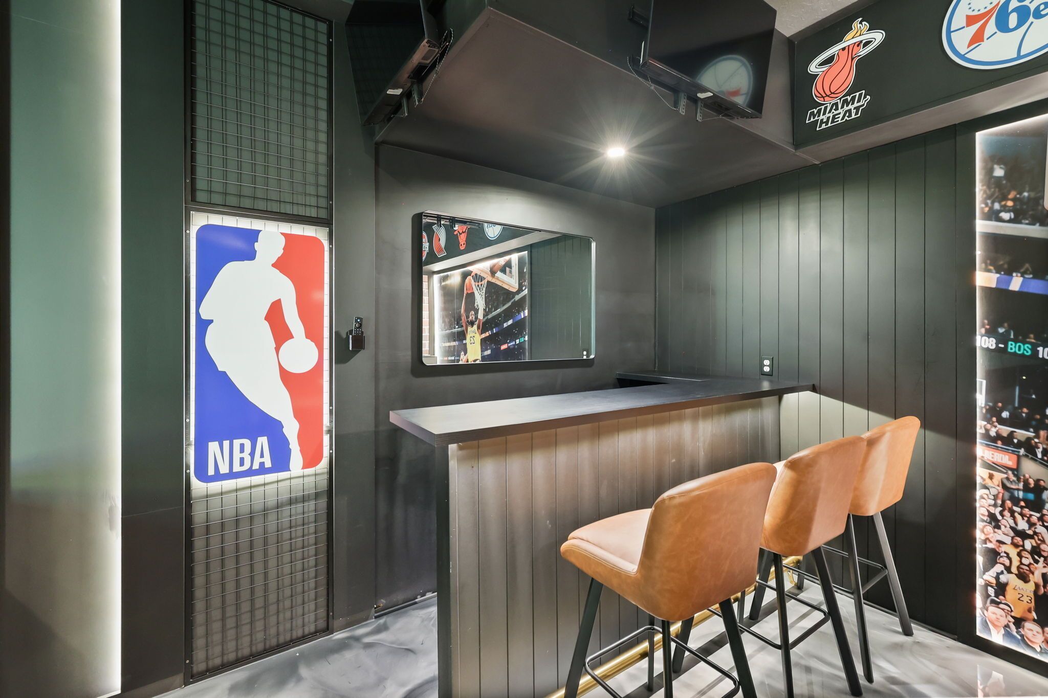 Een barruimte met basketbalthema, inclusief een groot NBA-logo, een spiegelwand met een basketbalspeler en een logo van Miami Heat.