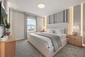 Ein modernes Schlafzimmer mit einem großen Bett, Nachttischen, einem Fernseher und Blick ins Freie.