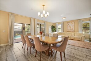A spacious living area with a dining table, comfortable seating, and a view of the outdoors. - 6 BD/ 6 BA/ Champions Gate (1510 RF) (Davenport)