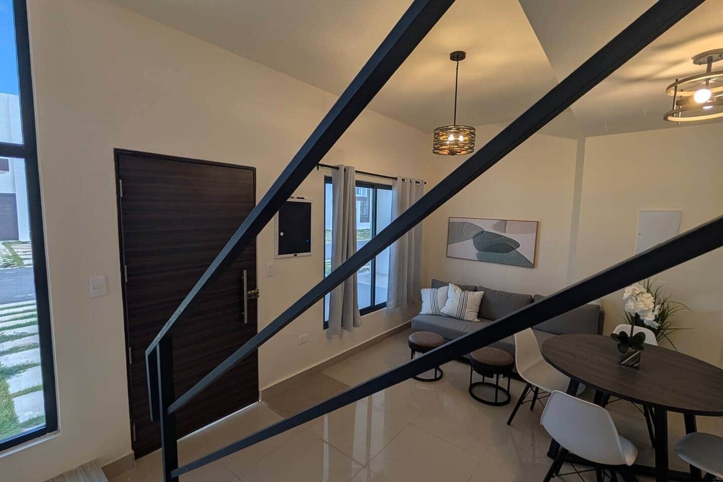 A modern interior with a staircase, a dining area, and a sofa.