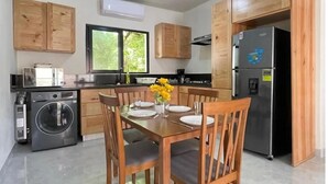 Una cocina moderna con armarios de madera, una mesa de comedor lista para cuatro personas, una lavadora y un refrigerador.