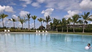 Une piscine aux eaux cristallines, avec des palmiers et des chaises longues en arrière-plan.