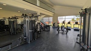 Une salle de sport moderne équipée de divers appareils d’exercice, dotée de grandes fenêtres et offrant une vue sur l’extérieur.