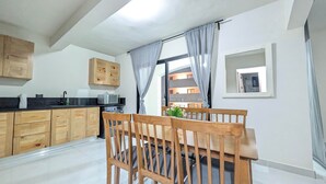 Una cocina moderna con armarios de madera, una mesa de comedor con sillas, un microondas y una ventana con cortinas.