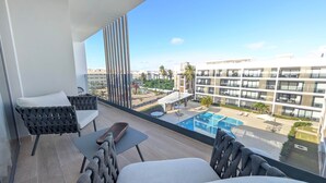 A balcony with a view of a swimming pool and adjacent buildings. - Cana Life Luxury | Azure Sky Penthouse (Punta Cana)