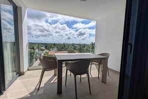 Ein Balkon mit Tisch und Stühlen, Blick zum Himmel und eine entfernte Landschaft.