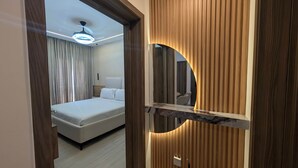 Una camera d'hotel moderna con un letto, una ventola a soffitto, uno specchio circolare e pannelli in legno.