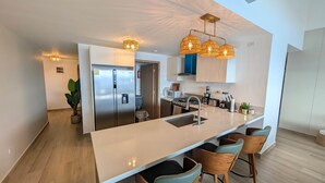 Una cocina moderna con una isla central, electrodomésticos de acero inoxidable e iluminación colgante.