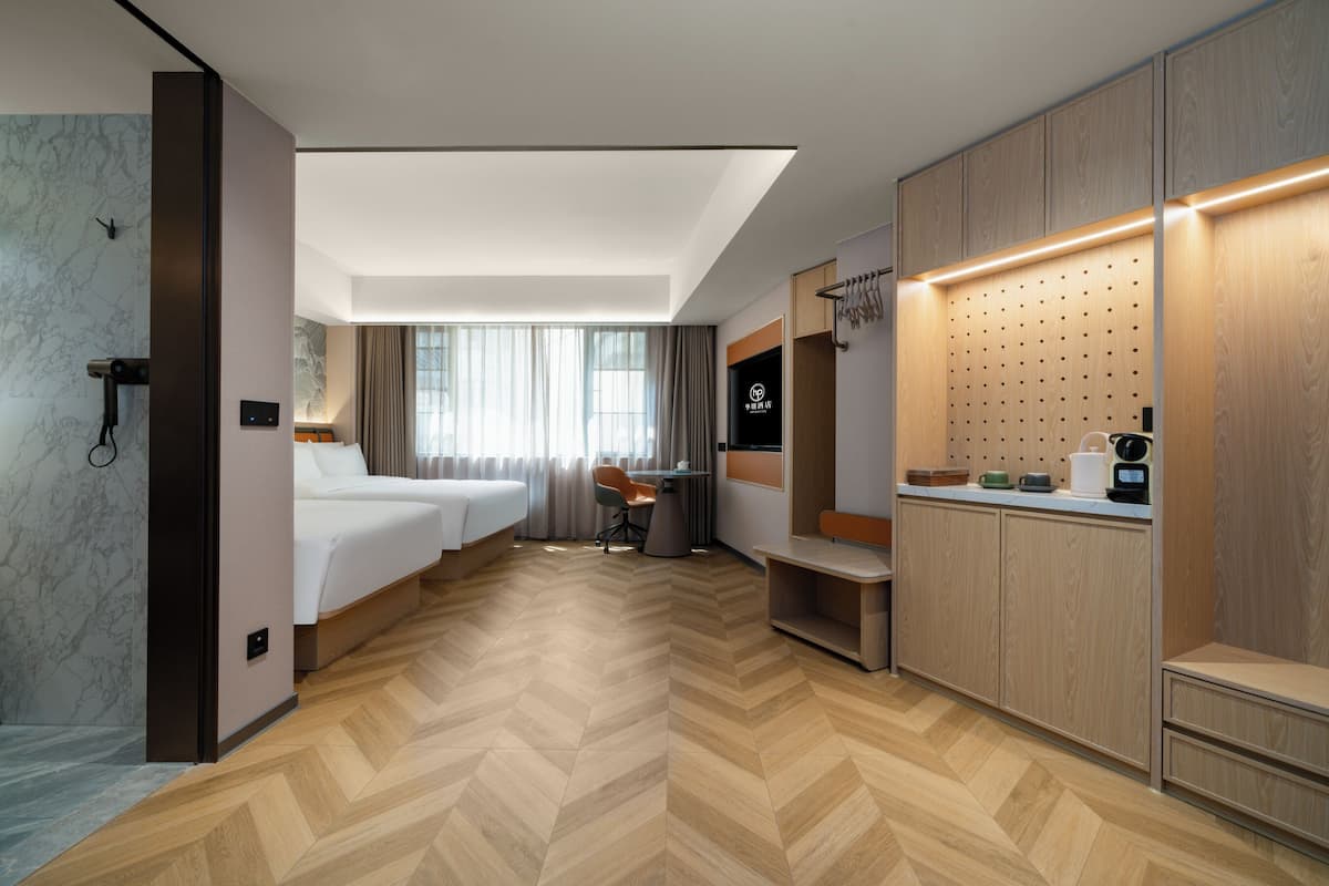 A hotel room with a bed, a desk, a chair, a wardrobe, and a bathroom.