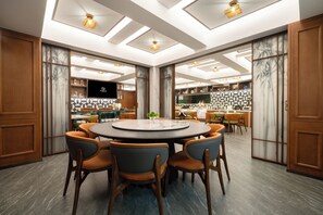 A modern dining area with a round table, multiple chairs, and a kitchen in the background. - Huapeng International Guangzhou (Guangzhou)