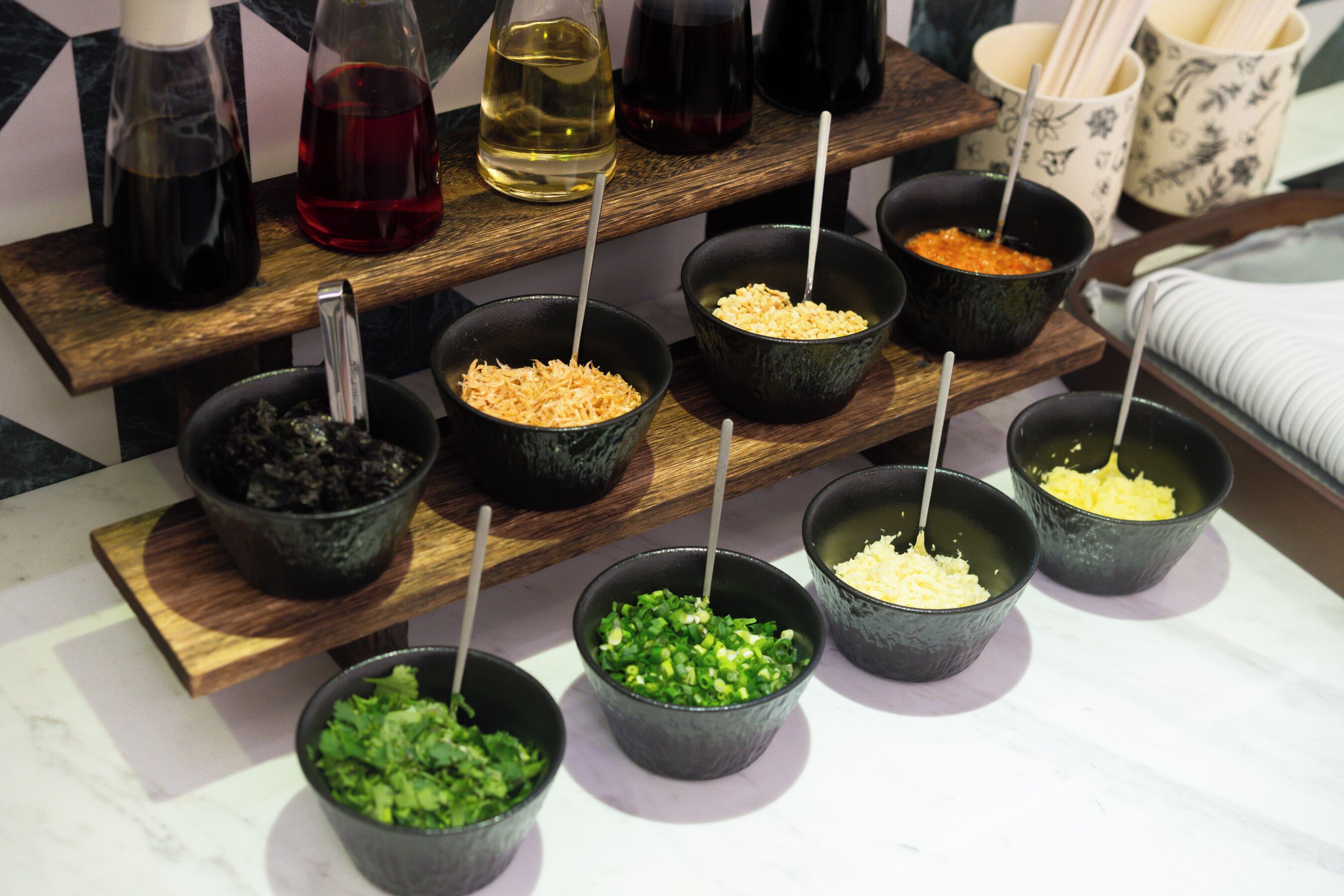 Une planche de service en bois, sur laquelle sont disposés différents bols contenant divers aliments et condiments.