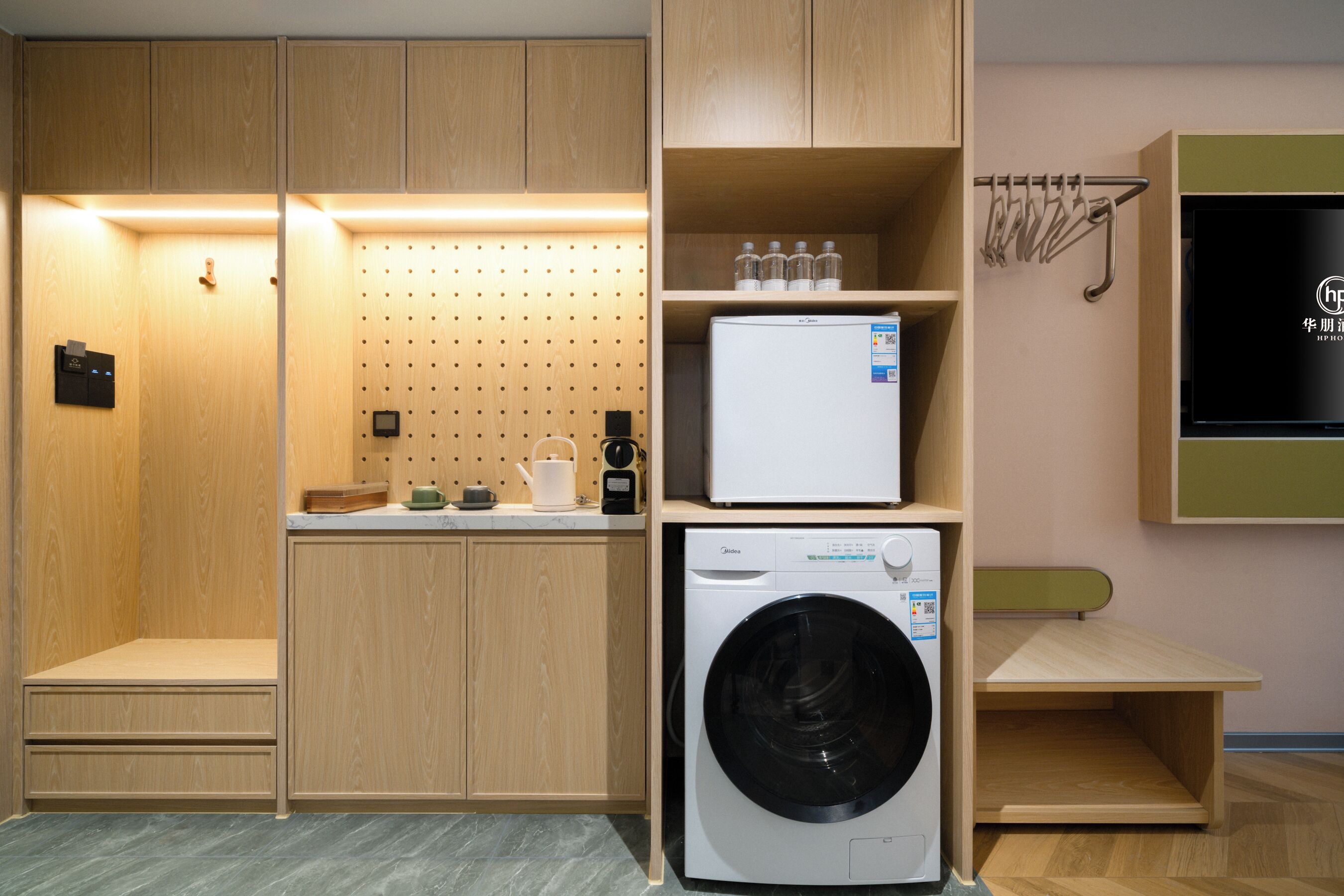 Un espace buanderie compact comprenant un lave-linge, un petit réfrigérateur et un étendoir.