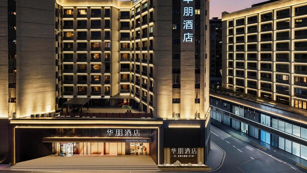 A modern hotel building with multiple floors, a prominent entrance, and illuminated signage. - Huapeng International Guangzhou (Guangzhou)