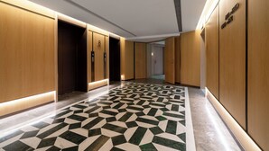 A hallway with wooden paneling, a patterned floor, and an elevator. - Huapeng International Guangzhou (Guangzhou)