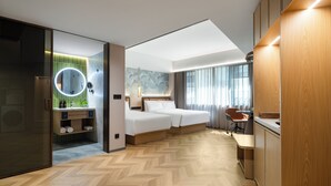 A modern hotel room with a large bed, a desk, a chair, a mirror, and a bathroom with a circular mirror. - Huapeng International Guangzhou (Guangzhou)