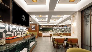 A hotel lobby with a buffet area, a seating area with tables and chairs, and a large screen displaying the hotel name. - Huapeng International Guangzhou (Guangzhou)