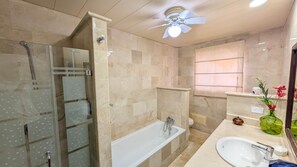 A bathroom with a glass shower enclosure, a bathtub, a sink, and a ceiling fan. - Cana Life Luxury | Villa Cueva (Punta Cana)