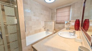 A bathroom with a bathtub, a sink, a mirror, and a shower area. - Cana Life Luxury | Villa Cueva (Punta Cana)