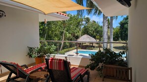Ein Balkon mit Blick auf einen Pool, umgeben von Kübelpflanzen und Liegestühlen.