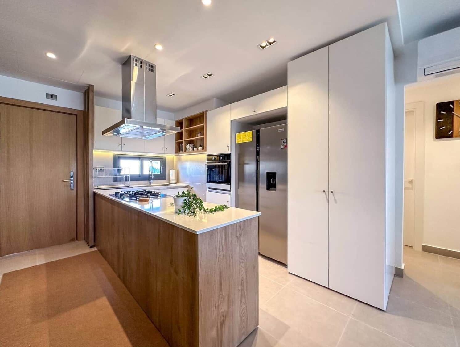 Eine moderne Küche mit Kochinsel, Backofen und großem Kühlschrank.