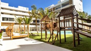 Um resort com piscina, estruturas de recreação em madeira e um edifício moderno ao fundo.