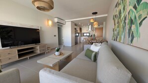 Uma sala de estar moderna com televisão de tela plana, sofá, mesa de centro e obra de arte na parede.