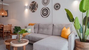 A living room with a grey sofa, wooden coffee table, and a large potted plant. - Cana Life Luxury | Sapphire Sky Pool Penthouse (Punta Cana)