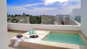 A rooftop pool with a clear view of palm trees and a modern building in the background. - Cana Life Luxury | Sapphire Sky Pool Penthouse (Punta Cana)