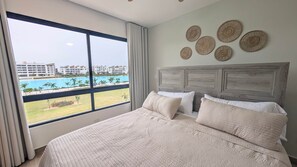 Ein Hotelzimmer mit einem großen Bett, Blick auf einen Pool und einem Balkon.