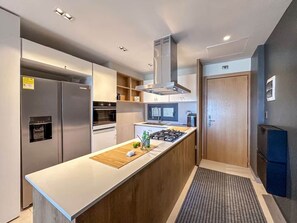 A modern kitchen with a central island, built-in oven, and stainless steel appliances. - Cana Life Luxury | Sky Palace Penthouse (Punta Cana)