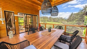 A wooden deck with a dining table, chairs, and hanging lights. - Cana Life Luxury Eco | Pineview Jimenoa Villa (Jarabacoa)