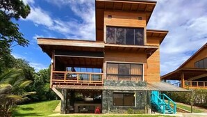 Una casa moderna de dos pisos con balcón, base de piedra y escalera.