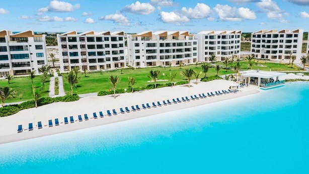 Een resort met een zwembad, meerlaags gebouwen en een strand.