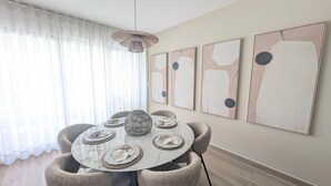 Een eetruimte met een ronde tafel, vier stoelen en abstracte kunst aan de muur.