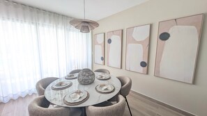 A dining area with a round table, four chairs, and abstract art on the wall. - Cana Life Luxury | City Beach – Crystal Lagoon View (Punta Cana)