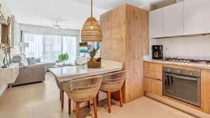 Una cocina moderna con una isla central, armarios de madera, estufa a gas y un comedor con sillas de mimbre.