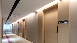 A hotel hallway with a carpeted floor, doors, and a digital display showing room number 8702. - Lavande International Huawei Guangzhou  (Guangzhou)