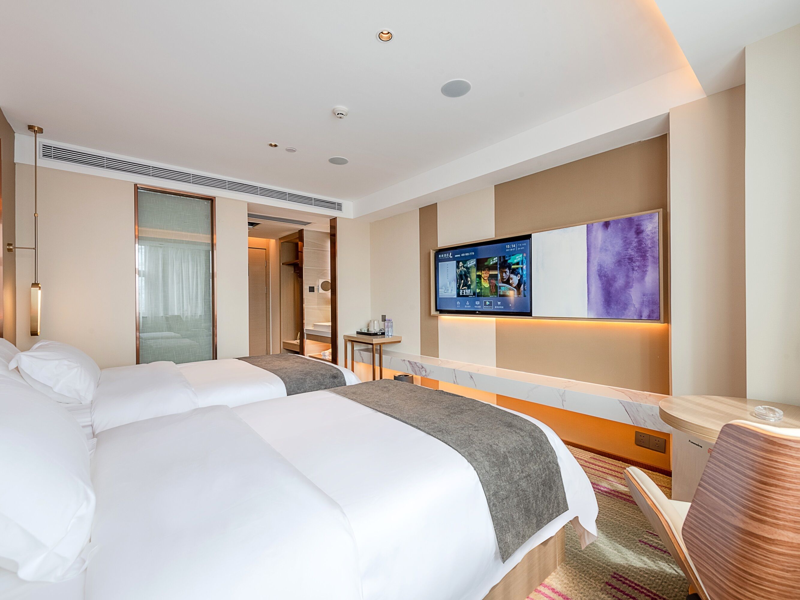 Una habitación de hotel con dos camas, televisión, escritorio y vestidor.