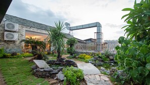 A courtyard with a stone pathway, potted plants, and a building with air conditioning units. - Lavande International Huawei Guangzhou  (Guangzhou)