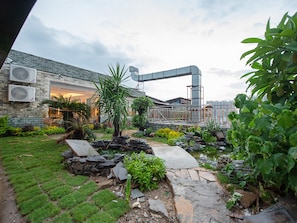 A courtyard with a stone pathway, potted plants, and a building with air conditioning units. - Lavande International Huawei Guangzhou (Guangzhou)