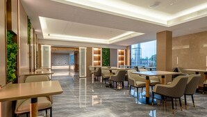 A modern hotel lobby with a reception desk, seating area, and large windows offering a city view. - Lavande International Huawei Guangzhou  (Guangzhou)