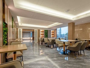 A modern hotel lobby with a reception desk, seating area, and large windows offering a city view. - Lavande International Huawei Guangzhou  (Guangzhou)