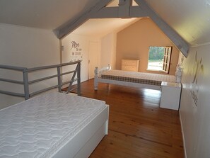 A bedroom with a bunk bed, a small dresser, and a window with a view of greenery. - Quiet cottage (Martel)