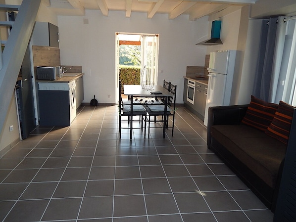 A spacious kitchen with a dining area, a sofa, and a view of the outdoors. - Quiet cottage (Martel)