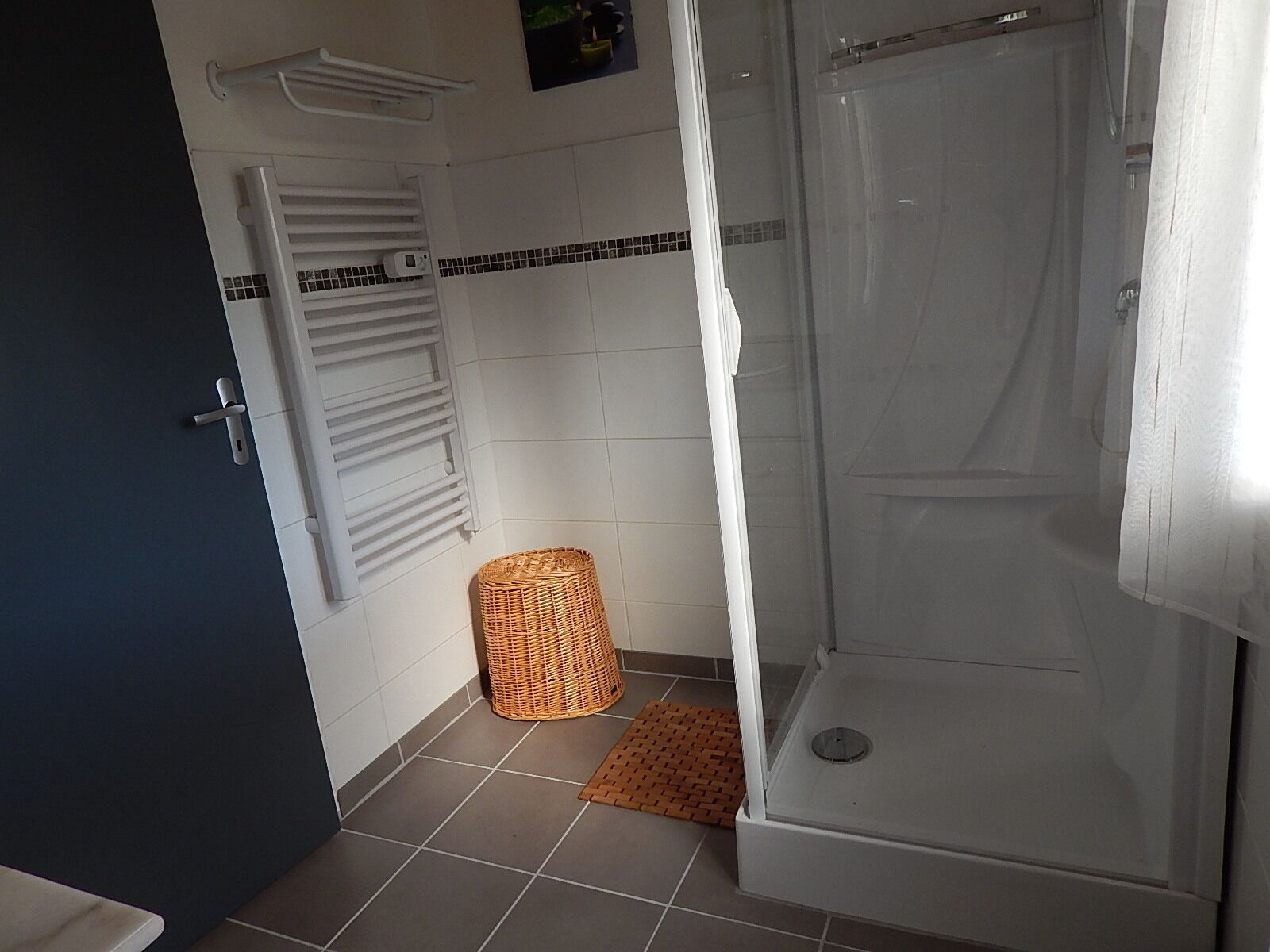 A bathroom with a shower, a towel rack, and a wicker basket on the floor.