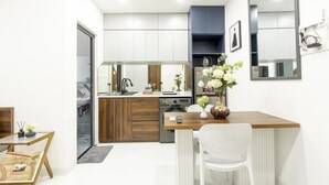A modern kitchen with a dishwasher, a coffee machine, and a vase with flowers on the counter. - Nhà Sài Gòn (Ho Chi Minh City)
