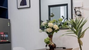 A modern kitchen with white cabinetry, a wooden countertop, and a vase with flowers. - Nhà Sài Gòn (Ho Chi Minh City)