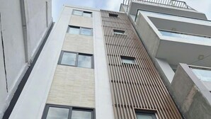 A multi-story building with a modern architectural design, featuring a combination of white and beige facades, large windows, and a sloped roof. - Nhà Sài Gòn (Ho Chi Minh City)