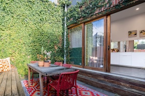 A dining area with a table, chairs, and a potted plant. - Chic Carlton Retreat | Rooftop, Central, Spacious (Carlton)